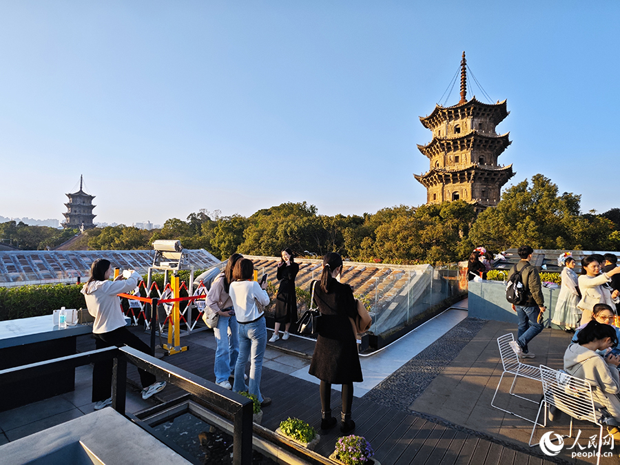 游客們在西街游客服務(wù)中心天臺上與東西雙塔合影留念。人民網(wǎng) 黃東儀攝