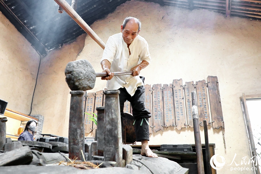 從事古法山茶油制作50年的游信玉現(xiàn)場掄錘榨油。人民網(wǎng) 李唯一攝