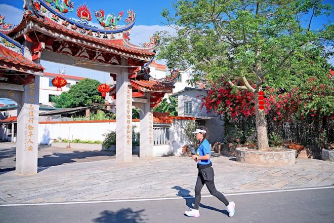 在特色建筑映襯下，一名選手在村道上奔跑。漳州市龍文區(qū)融媒體中心供圖