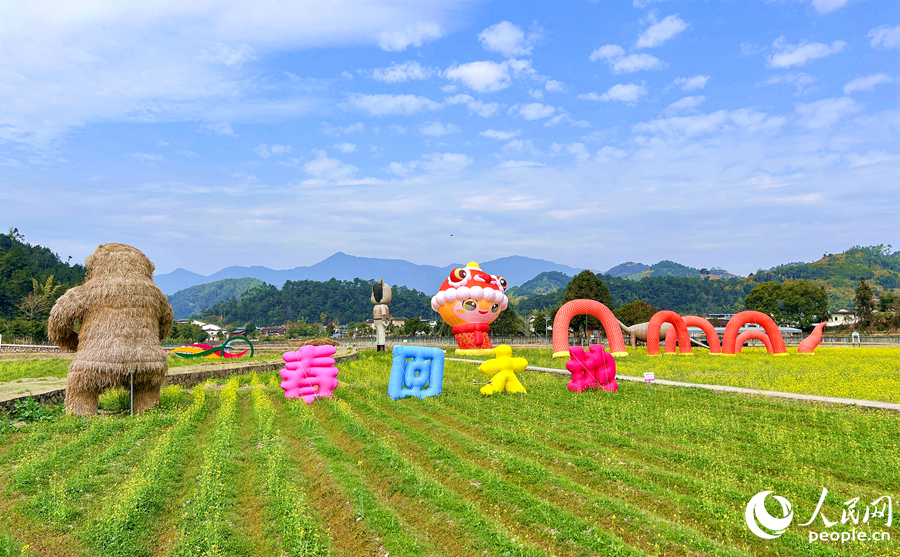 花田里的卡通蛇造型和“春回大地”字樣，構(gòu)成一幅充滿生機(jī)的春日畫卷。華安縣融媒體中心供圖