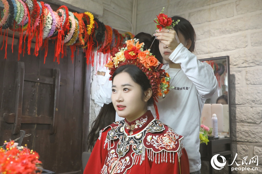 在秀發(fā)被盤成圓髻后，由鮮花串成的花圍被簪在頭上。人民網(wǎng) 李唯一攝