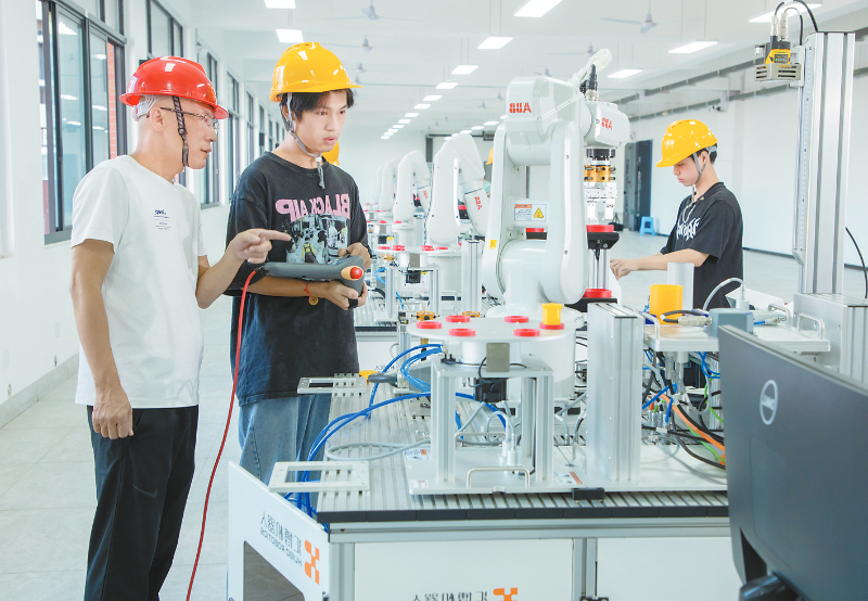 全國(guó)先進(jìn)工作者林福（左）指導(dǎo)學(xué)生操作工業(yè)機(jī)器人