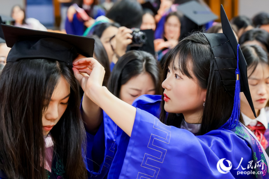 畢業(yè)生互相整理儀容。人民網(wǎng)記者 陳博攝